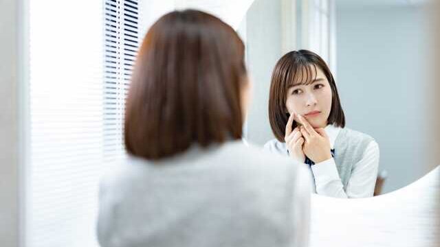 鏡の前で肌を気にする女子高生